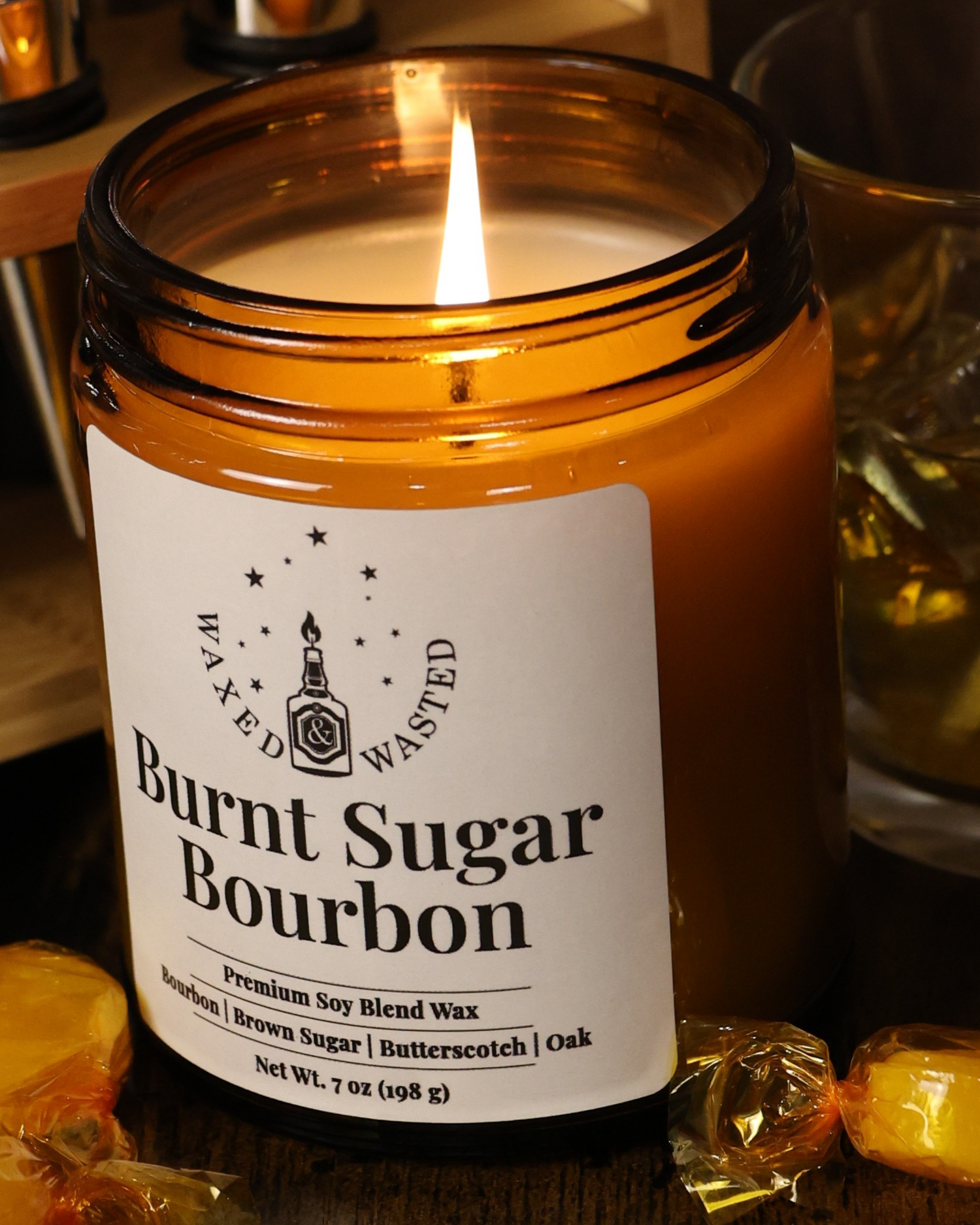 Candle in a glass jar labeled 'Burnt Sugar Bourbon' on a wooden surface with a blurred background.